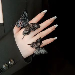 Close-up of elegant black butterfly open rings on hand with stylish manicured nails