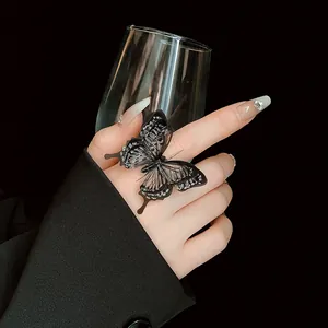 Detail view of an elegant black butterfly mesh ring with rhinestones on a finger.