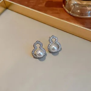 Detail shot of silver pin gourd earrings with sparkling zircon and white pearls.