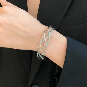 Primo piano di un bracciale argento a torsione irregolare indossato al polso con un blazer nero