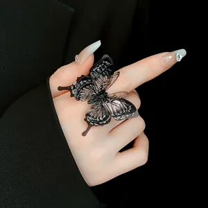 Detailed view of an elegant black butterfly open ring with sparkling accents on a finger.