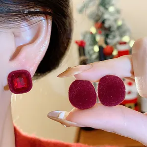 Elegant red flocked stud earrings with crystal rhinestones in a festive holiday setting