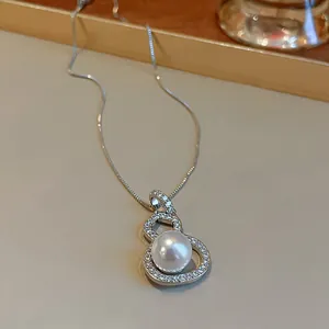 Close-up of elegant gourd-shaped necklace pendant with sparkling zircons and a white pearl