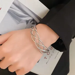 Vista dettagliata di un bracciale rigido ritorto minimalista argento al polso.