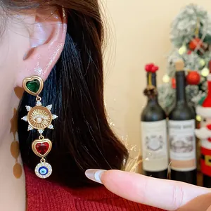 Detailaufnahme von Hängeohrringen mit grünen und roten Herzen, Sonnen- und Auge-Anhängern