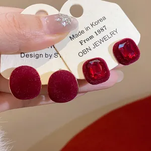 Detailed view of red flocked geometric stud earrings with inset crystal rhinestones