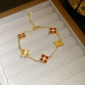Close-up of a luxury 18K gold plated bracelet featuring red and gold clover motifs.