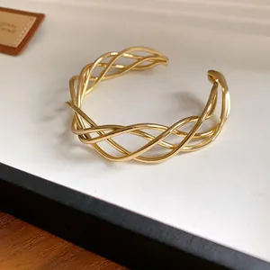 Primo piano del bracciale rigido dorato intrecciato che mostra la trama dei fili d'oro