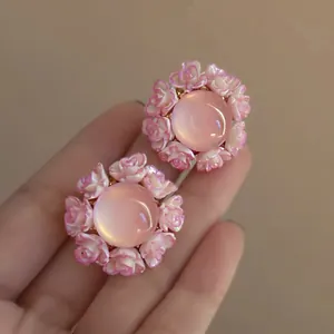 Elegant hand-held pink resin flower earrings with a luminous central cabochon stone