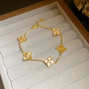 Luxury 18K gold plated bracelet with pink shell and zircon clover motifs in jewelry tray.