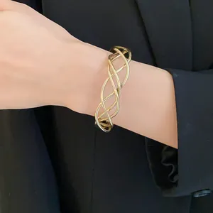 Vista dettagliata di un bracciale a polsino dorato a spirale irregolare su sfondo nero.