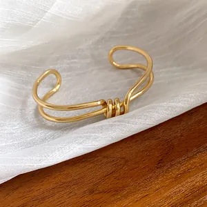 Vista dettagliata del bracciale a polsino dorato ritorto irregolare con finitura lucida