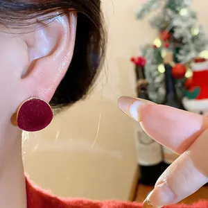 Close-up of elegant red flocked round stud earring worn on ear for holiday style