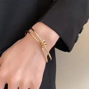 Vista dettagliata di un elegante bracciale rigido dorato intrecciato minimalista al polso