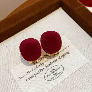 Macro view showing the soft red flocked texture of these elegant gold-toned geometric stud earrings