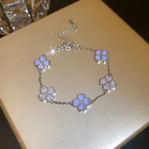 Close-up of a silver clover bracelet with zircon and light blue shell details