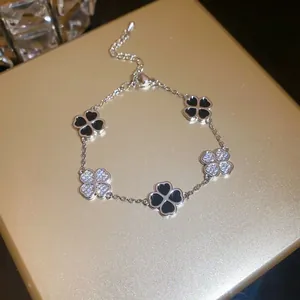 Detailed view of silver-toned bracelet featuring black and crystal clover charms