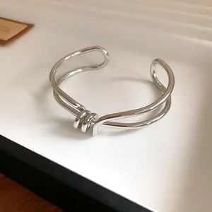 Primo piano di un bracciale rigido argento ritorto irregolare con dettaglio a nodo