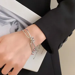 Primo piano di un bracciale rigido aperto argento dal design ritorto unico