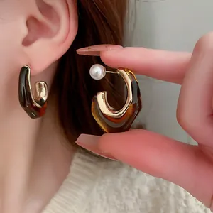 Close-up of Maillard style brown resin hoop earrings with gold-tone accents