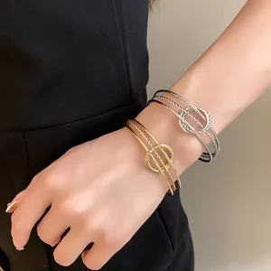 Bracciali rigidi aperti intrecciati irregolari oro e argento sul polso della modella