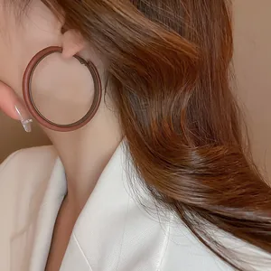 Close-up of a large coffee brown Maillard style leather hoop earring worn by a model