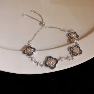 Close-up of 18K gold plated zircon shell clover charm on a sliding bracelet.