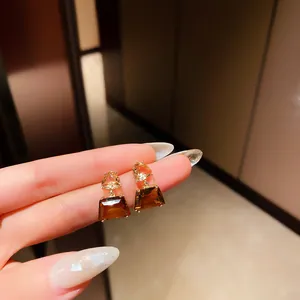 Close-up of geometric amber and brown gemstone drop earrings with gold-toned setting