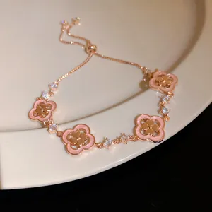Close-up view of elegant rose gold drawstring bracelet with pink shell clovers and zircons