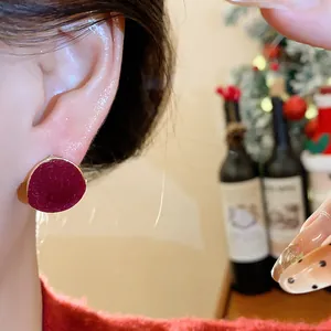 Macro view of a wine red flocked geometric round stud earring worn on an earlobe