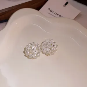 Close-up of sparkling clear crystal floral stud earrings on a decorative plate