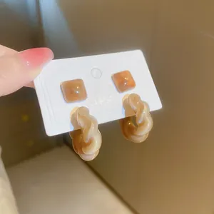 Detailed view of caramel marble twisted hoop earrings and square studs on card