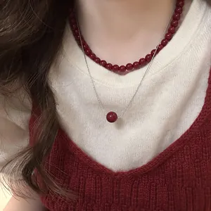 Close-up detail of double-layered Ancora red bead necklace on elegant knitwear