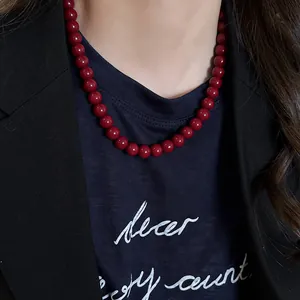 Close-up detail of a vintage style Ankara red bead necklace worn over a black blazer.