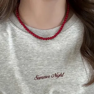 Macro detail of a vintage style red bead necklace elegantly worn on a gray heathered t-shirt