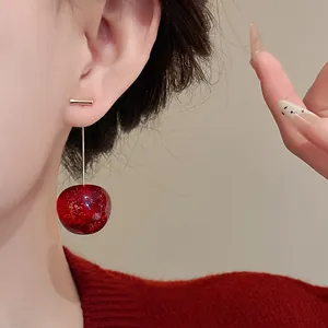 Κοντινό πλάνο ενός ζωντανού κόκκινου σκουλαρικιού κεράσι με χρυσό γκλίτερ στο αυτί