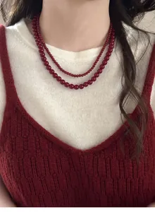 Elegant close-up of double-layer vintage red bead necklace worn on a white sweater