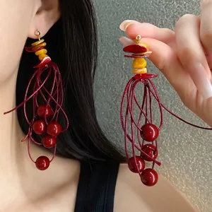 Handcrafted red beaded tassel earrings with yellow acrylic accents on an Asian model