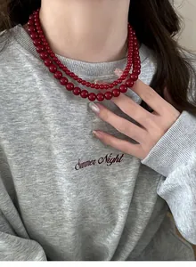 Detail shot of a vintage double-layered red beaded necklace worn on a grey sweater