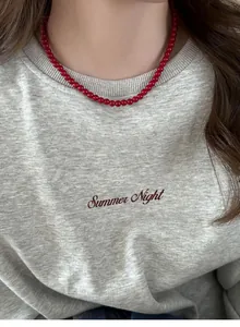 Red beaded transfer necklace shown on a grey sweatshirt for a vintage autumn look.