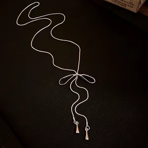 Macro detail of elegant silver bowknot tassel necklace with adjustable slider chain
