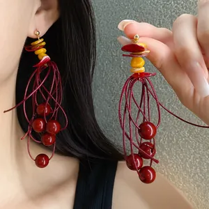 Detail of red beaded tassel earrings with geometric acrylic accents and silver needles