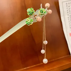 Dettaglio del fermaglio cinese vintage con accenti floreali verdi e nappa di perle