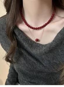 Detail view of a double-layered necklace featuring Ancora red beads and a delicate chain pendant