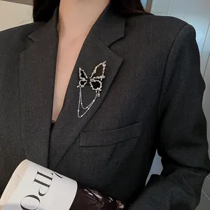 Élégante broche papillon noire avec chaînes en argent sur le revers d'un blazer gris.