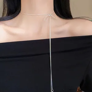 Close-up view of a minimalist silver bow-knot tassel drawstring necklace on model neck