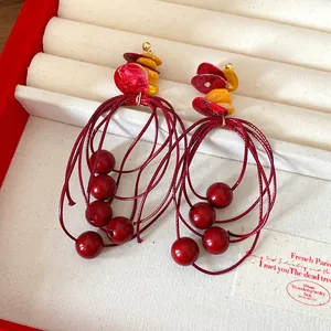 Detail view of retro red and yellow acrylic beaded tassel earrings in a jewelry box