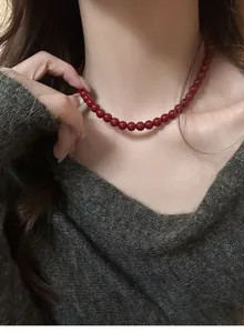 Detail view of an elegant retro red bead necklace worn on neck for winter.