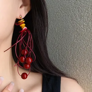 Detailed view of elegant red and amber acrylic beaded tassel earrings worn by model