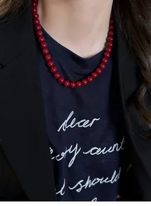 Close-up of vintage Ankora red bead necklace worn over a black blazer and t-shirt